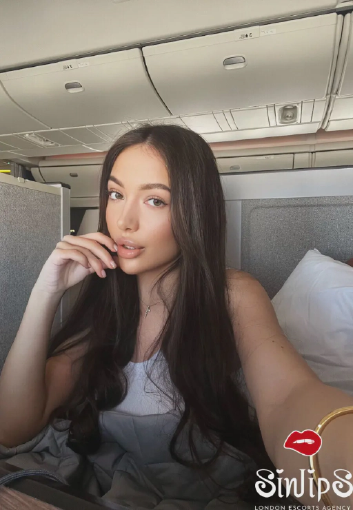 Felixa, stunningly beautiful Russian escort in London (South Kensington) with long brunette hair and brown eyes taking a selfie on plane